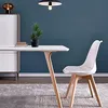 A white dining chair and table set against a blue wall. Produktbild-Vorschau