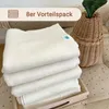 A stack of folded cream-colored cloths in a wooden tray, next to a woven basket with a green top. Produktbild-Vorschau