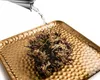 Water being poured onto a dried plant on a golden tray. Voir les images du produit