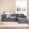A woman is reading a book on a large, dark gray sectional sofa in a living room. Sunlight streams in from a large window behind the sofa. Produktbild-Vorschau