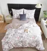 A neatly made bed with floral patterned bedding, pillows, and a throw blanket, set in a bedroom with a nightstand and a floor lamp. Podgląd zdjęcia produktu