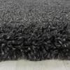 A close-up, low-angle view of a dark gray shaggy rug with a light-colored wooden floor visible underneath. Produktbild-Vorschau