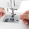 Close-up of hands threading a sewing machine needle. Produktbild-Vorschau