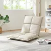 A beige floor chair is placed on a rug in a well-lit room with a window and a white cabinet in the background. Voir les images du produit