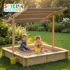 Two young children playing in a wooden sandbox with a canopy in a garden. Produktbild-Vorschau