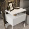 A white nightstand with a framed picture and a lamp on top, placed next to a bed. Náhled obrázku produktu
