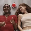 A man and a woman are lying down and laughing, with a portable speaker between them. Produktbild-Vorschau