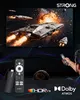 A TV screen displaying a space battle scene, with a streaming stick and remote control in the foreground, and two people watching. Náhled obrázku produktu