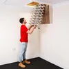 A man is installing a retractable attic ladder in a room. Produktbild-Vorschau