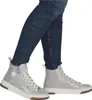 A person wearing blue jeans and silver high-top sneakers. Voir les images du produit