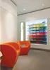 A retail store interior with two orange chairs in the foreground and a display of colorful folded shirts in the background. Voir les images du produit