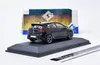 A black Volkswagen Golf VIII R model car is displayed on a black stand, with its original packaging in the background. Produktbild-Vorschau