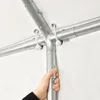 A hand is shown adjusting a metal pole on a tent frame. Produktbild-Vorschau
