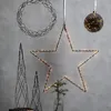 Decorative Christmas lights in various shapes including a star, wreath, and trees, displayed against a gray wall. Podgląd zdjęcia produktu