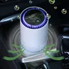 A white air purifier with a blue light ring is placed in a car's center console. Green wavy lines indicate airflow, and small green leaf icons float around the device. Produktbild-Vorschau