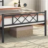 A close-up view of a black metal bed frame with a diamond pattern on the headboard, showing the mattress and a storage basket underneath. Podgląd zdjęcia produktu