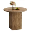 A round wooden dining table with a fluted pedestal base, decorated with a vase of flowers and a small bowl of fruit. Produktbild-Vorschau