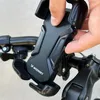 A hand is shown adjusting a black Wozinsky phone holder mounted on a bicycle handlebar. Produktbild-Vorschau