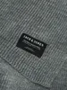A close-up view of a gray knitted scarf with a black label. Anteprima dell’immagine prodotto