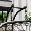 Close-up of the hanging mechanism of a swing chair, showing the metal frame, springs, and chains, with a wooden wall and greenery in the background. Produktbild-Vorschau
