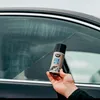 A hand holding a can of anti-fog spray next to a car window. Podgląd zdjęcia produktu