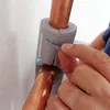 A hand is shown applying insulation to copper pipes. Produktbild-Vorschau