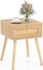 A light wood nightstand with a rattan drawer front, a cup of coffee, and a vase of dried flowers on top, set against a white background. Náhled obrázku produktu