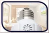 A close-up of a light bulb with a timer dial, set against a blurred background of a room. Produktbild-Vorschau