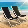 Two black deck chairs on a sandy beach with the ocean in the background. Anteprima dell’immagine prodotto