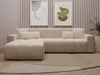 A modern beige sectional sofa with an ottoman in a living room setting, with abstract art on the wall. Produktbild-Vorschau