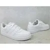 A pair of white Adidas sneakers are displayed on a textured gray and white surface. Anteprima dell’immagine prodotto