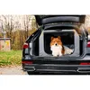 A dog is sitting in a portable dog crate in the trunk of a car. Produktbild-Vorschau