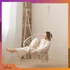 A woman relaxing in a macrame hanging chair indoors. Produktbild-Vorschau
