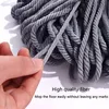 A hand is holding a strand of gray mop fibers, with a pile of similar fibers in the background. Voir les images du produit