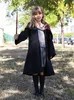 A young girl dressed as Hermione Granger stands outdoors holding a wand. Produktbild-Vorschau