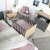A nursery room with a crib attached to a bed, a dresser, and a chair. Produktbild-Vorschau