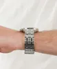 A close-up side view of a man's wrist wearing a silver watch with a black face. Náhled obrázku produktu