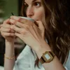 A woman is drinking from a mug, wearing a watch. Produktbild-Vorschau