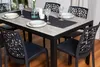 A dining table set with chairs, plates, and glasses, set up in a dining area. Anteprima dell’immagine prodotto