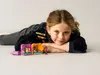 A young girl is lying on the floor with LEGO Friends Andreas' magical cube - pet shop in front of her. Náhled obrázku produktu