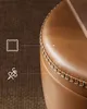 Close-up of a brown leather ottoman with decorative stitching. Náhled obrázku produktu