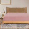 A pink fitted sheet on a bed with a wooden headboard and a side table. Produktbild-Vorschau