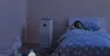 A child sleeping in a bed next to a Xiaomi air purifier in a dimly lit bedroom. Produktbild-Vorschau