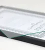 A close-up, angled shot of a black picture frame with a document inside, showing the glass edge. Produktbild-Vorschau