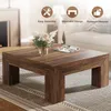 A square coffee table with a wood grain finish is shown in a living room setting, with a vase of flowers and a magazine on top. Three circular icons with text are displayed in the upper right corner. Voir les images du produit