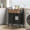 A laundry cart with two baskets and two drawers is placed next to a washing machine in a laundry room. Voir les images du produit