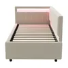 A beige upholstered bed frame with a slatted base and LED lighting at the headboard, shown from the side. Náhled obrázku produktu