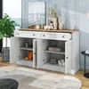 A white sideboard with a wooden top is shown in a room with a large window, a plant, and decorative items on top. The doors of the sideboard are open, revealing shelves with various items. Produktbild-Vorschau