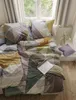 A neatly made bed with a geometric patterned duvet and pillows, placed near a window with curtains. Produktbild-Vorschau