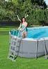 A woman in a teal swimsuit is climbing out of an oval above-ground swimming pool in a backyard setting. Anteprima dell’immagine prodotto